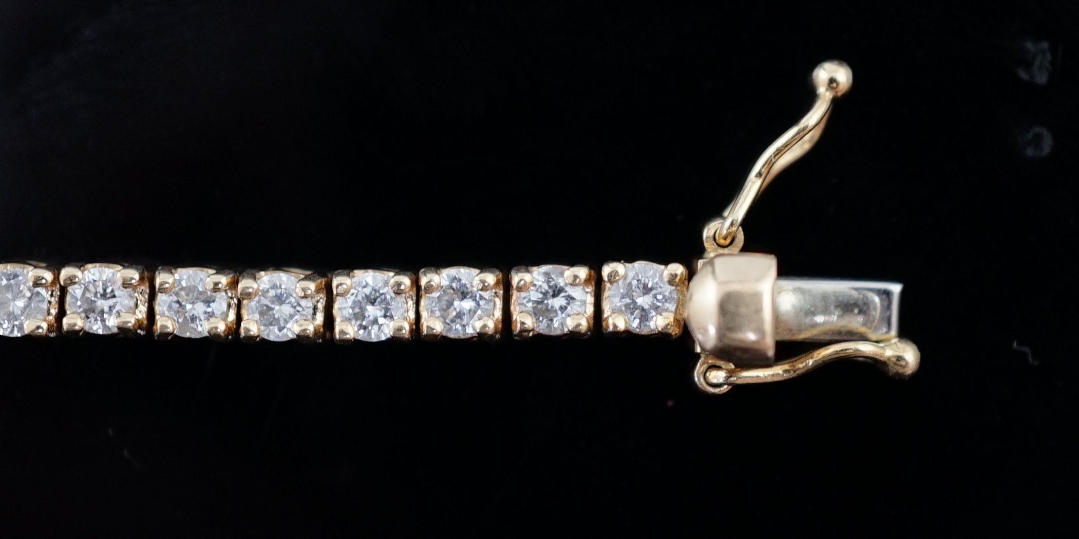A modern 18ct gold and fifty nine stone round brilliant cut diamond set line bracelet